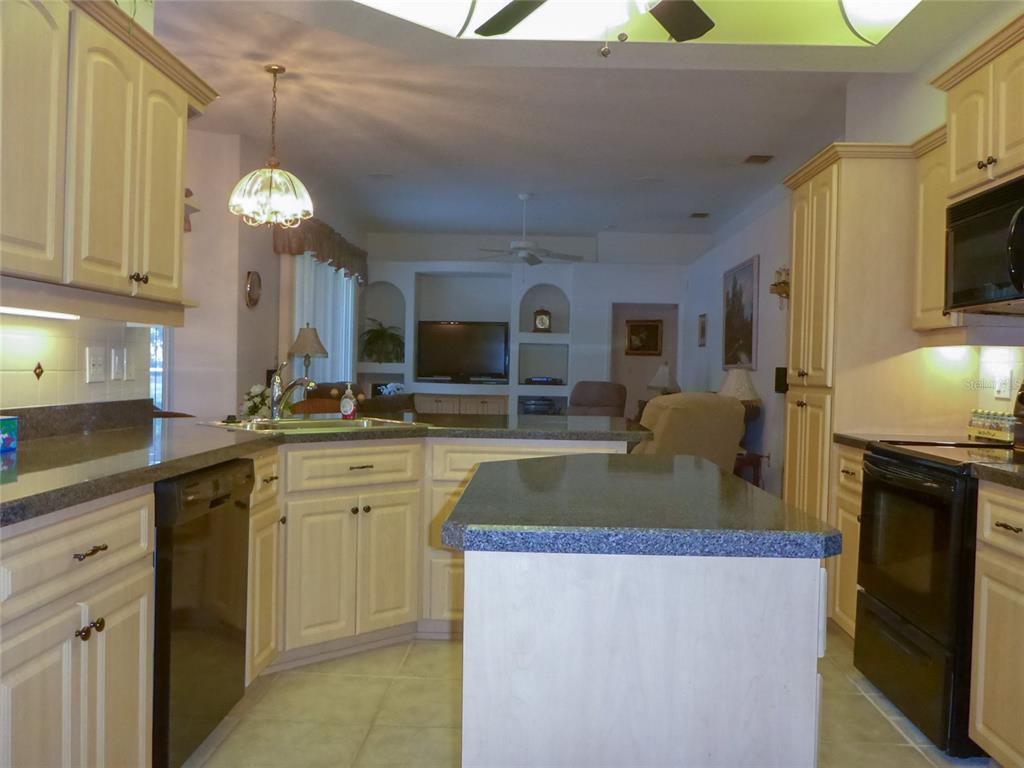 A kitchen with light-colored cabinets, dark countertops, and an island, opening into a living area — 12271 CENTRALIA RD, WEEKI WACHEE, FL