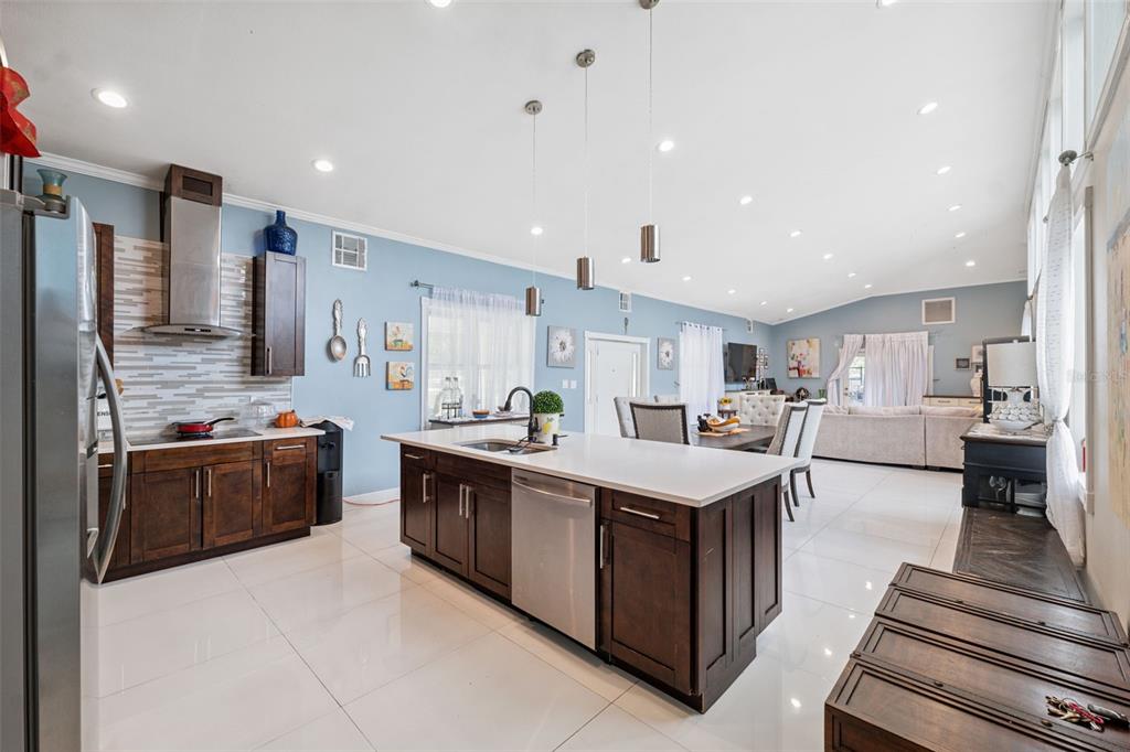 A modern kitchen features dark wood cabinets, white countertops, stainless steel appliances, and light blue walls — 4527 REDCOAT DRIVE, WESLEY CHAPEL, FL