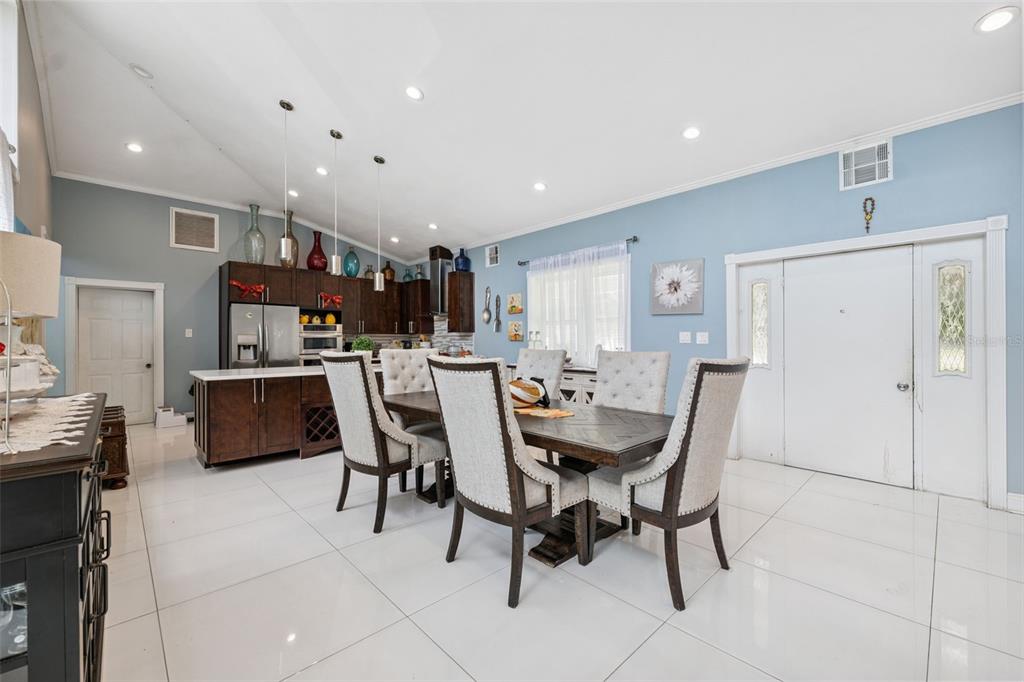 A dining area with a wooden table, upholstered chairs, and an open kitchen with cabinets — 4527 REDCOAT DRIVE, WESLEY CHAPEL, FL