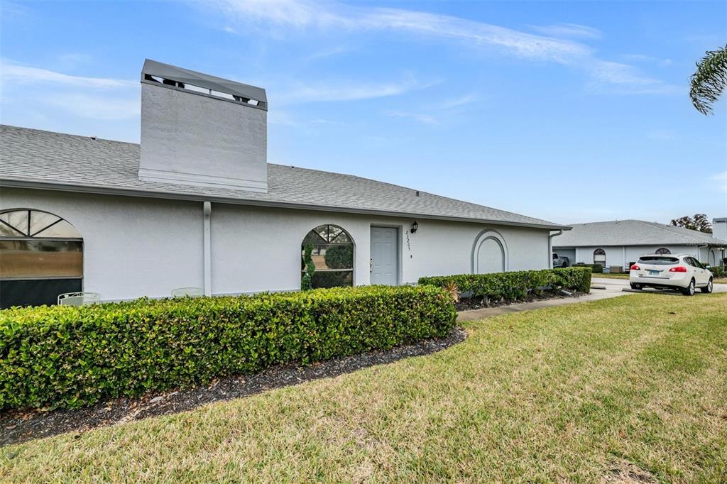 A single-story house with a gray roof, white stucco walls, and a manicured hedge — 23205 CLUB VILLAS DRIVE UNIT 30, LAND O LAKES, FL