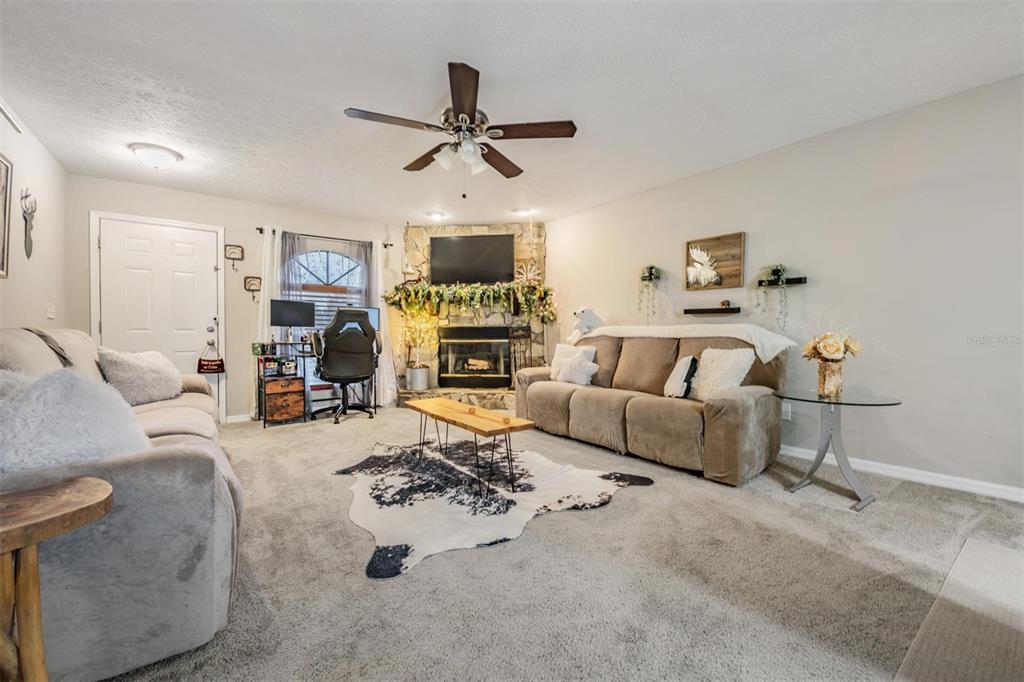 A living room features two sofas, a stone fireplace, a desk, and a cowhide rug — 23205 CLUB VILLAS DRIVE UNIT 30, LAND O LAKES, FL