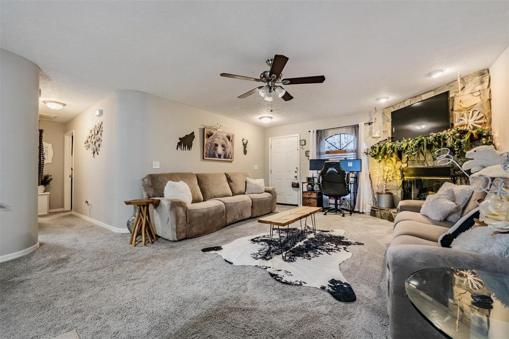 A living room features a stone fireplace, two sofas, a cowhide rug, and a desk — 23205 CLUB VILLAS DRIVE UNIT 30, LAND O LAKES, FL