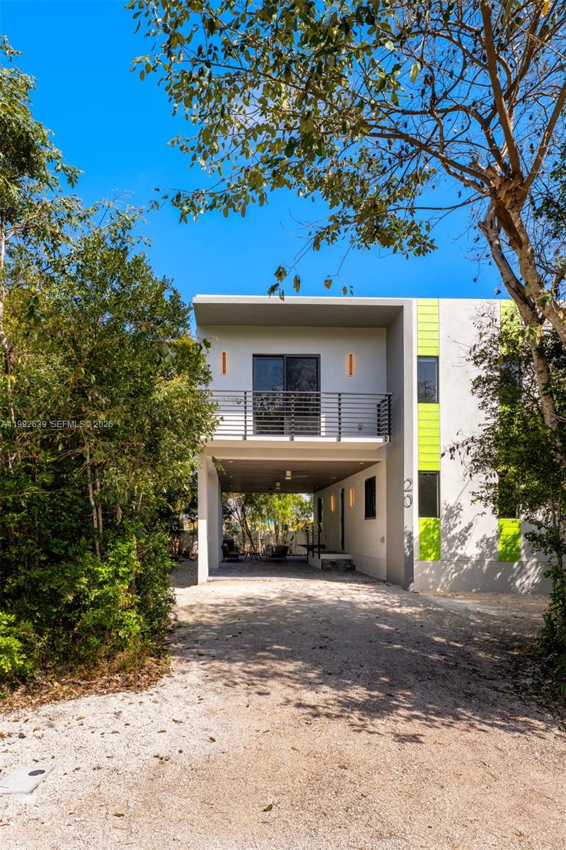 A modern two-story house with a gravel driveway and a covered ground-level parking area — 20 Coral Dr, Key Largo FL 33037, KEY LARGO, FL