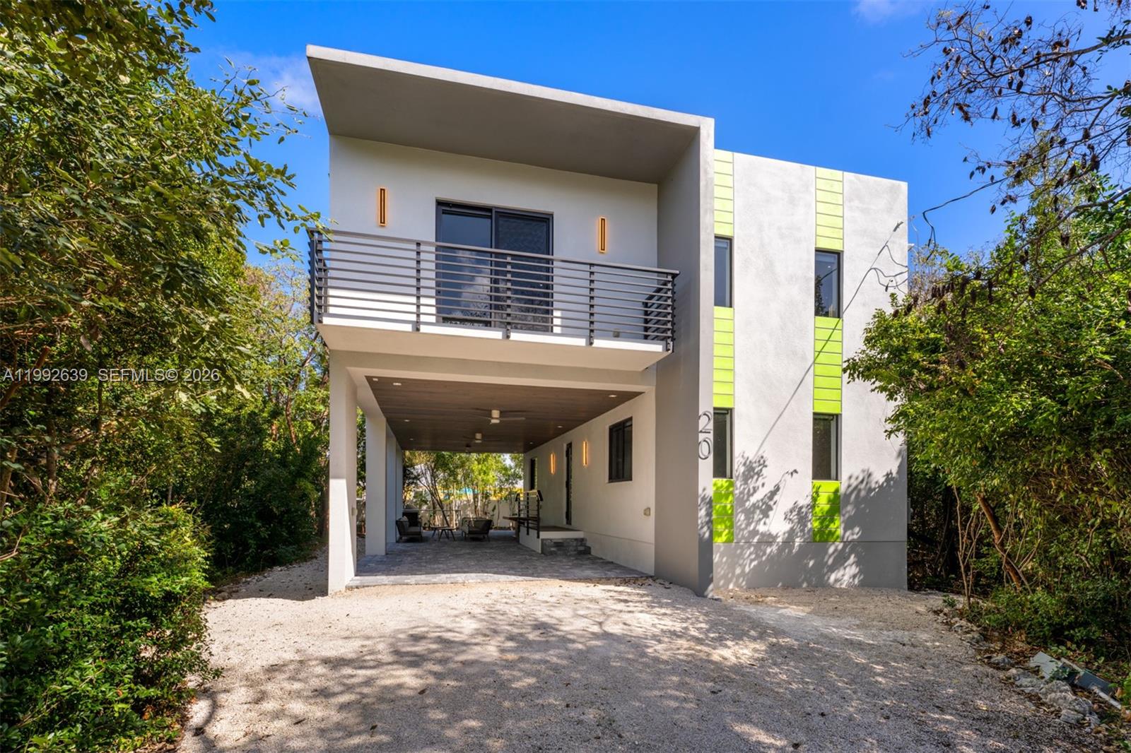 A modern two-story house features a covered ground-level parking area and a second-floor balcony — 20 Coral Dr, Key Largo FL 33037, KEY LARGO, FL
