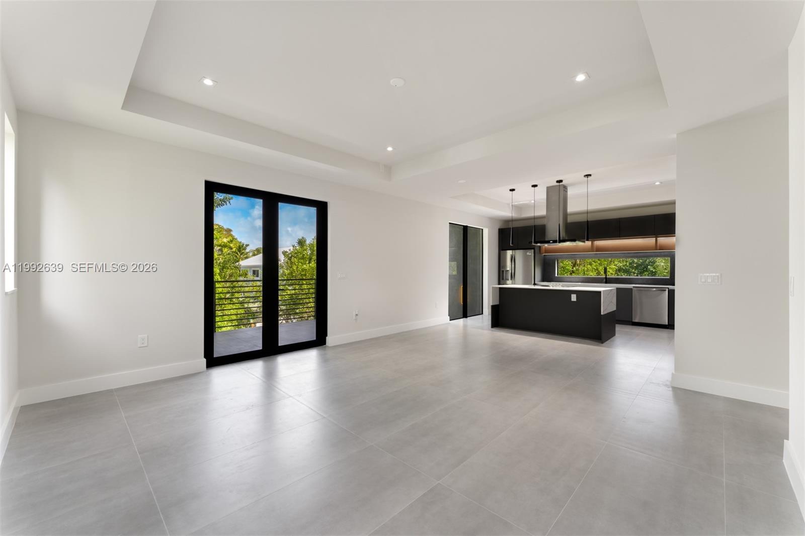 An open-concept kitchen and living area features gray tile flooring, white walls, and a balcony — 20 Coral Dr, Key Largo FL 33037, KEY LARGO, FL