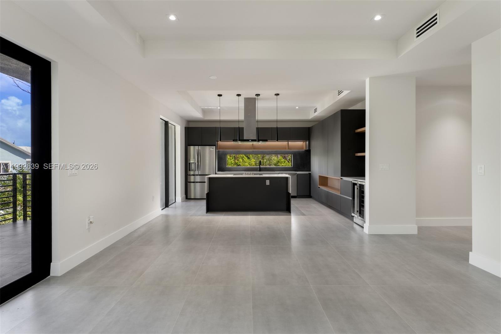 A modern kitchen features dark cabinetry, a central island, and large gray floor tiles — 20 Coral Dr, Key Largo FL 33037, KEY LARGO, FL