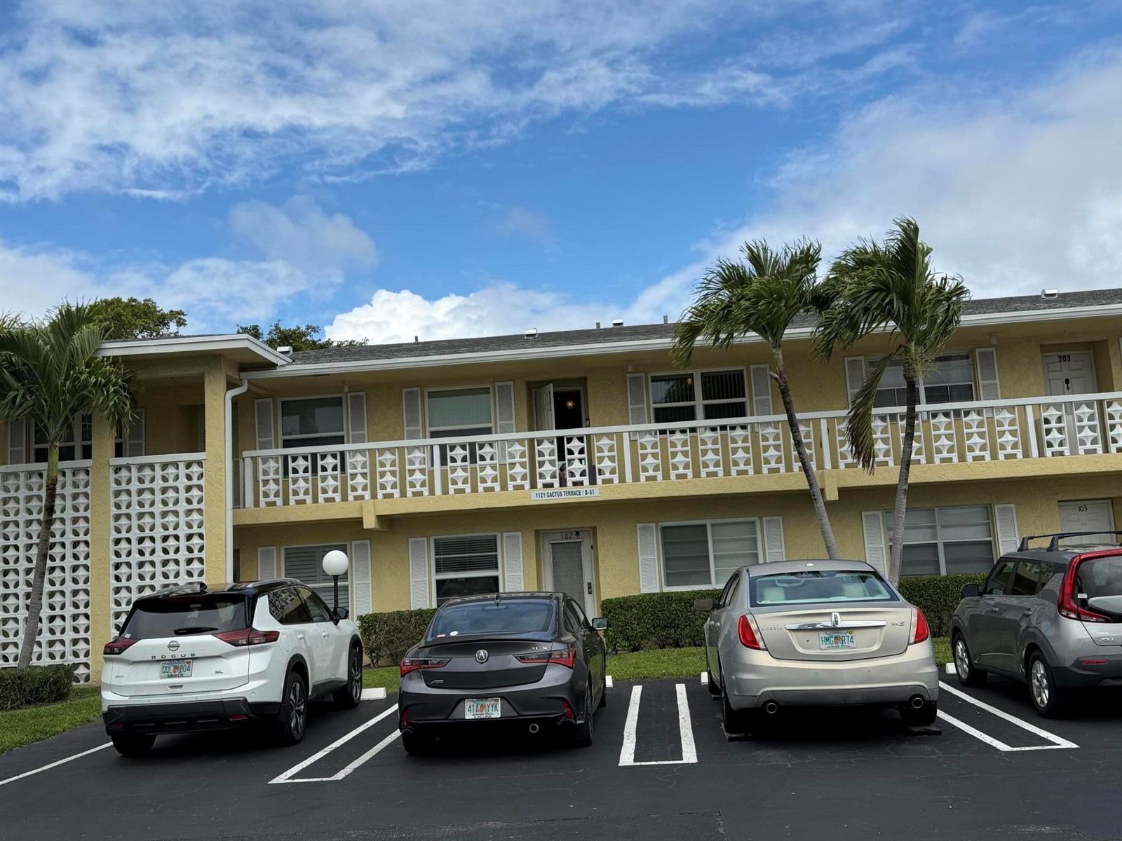 A two-story apartment building with a white balcony and four parked cars in front — 1121 Cactus Terrace # 202, Delray Beach FL 33445, DELRAY BEACH, FL