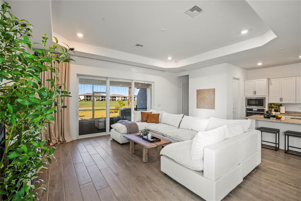 A living room with a white sectional sofa, wood coffee table, and sliding glass doors — 15916 N SUGAR HILL DRIVE, PUNTA GORDA, FL