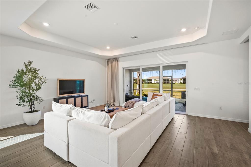 A living room with white walls, a large sectional sofa, and sliding glass doors to a patio — 15916 N SUGAR HILL DRIVE, PUNTA GORDA, FL