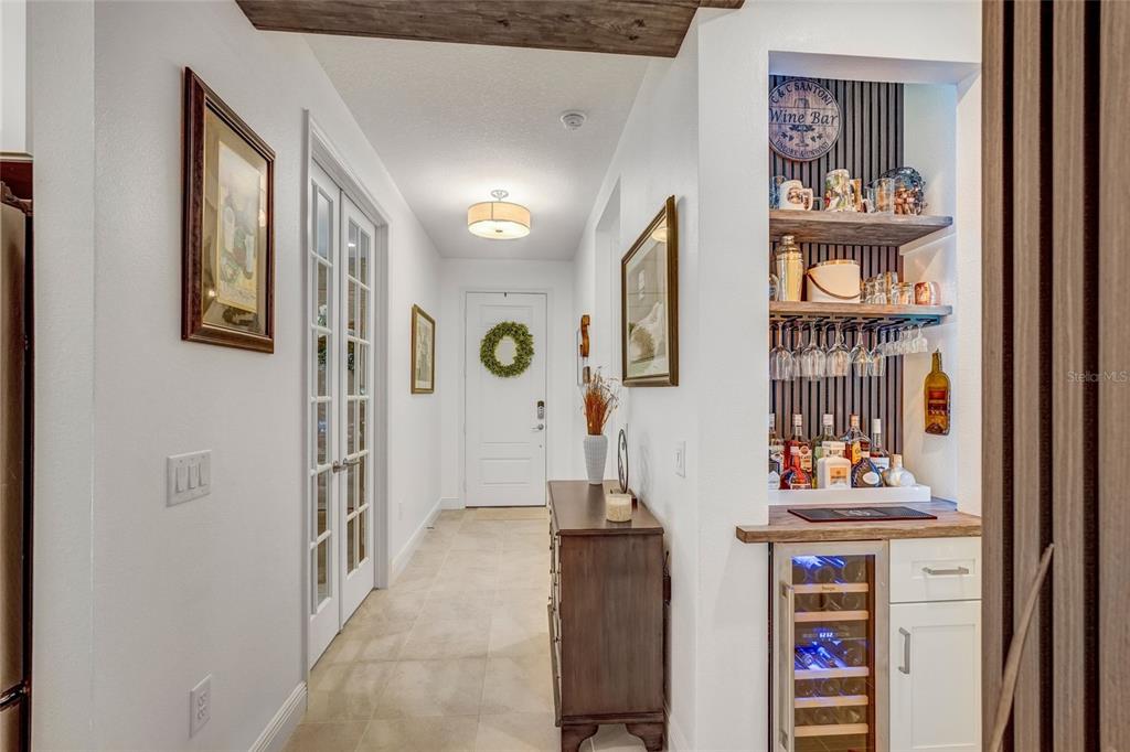 A hallway features a built-in bar, a wine cooler, and a white door with a wreath — 10233 LAKE WALES CIRCLE, SARASOTA, FL