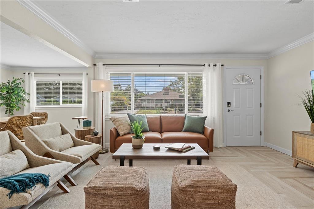 A living room features a brown leather sofa, two armchairs, ottomans, and light wood flooring — 2641 MARTIN STREET, SARASOTA, FL