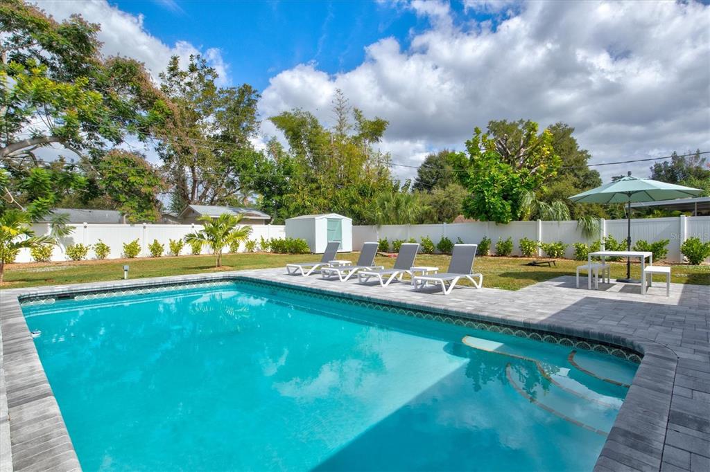 A backyard swimming pool with lounge chairs, a patio table, and a white privacy fence — 2641 MARTIN STREET, SARASOTA, FL