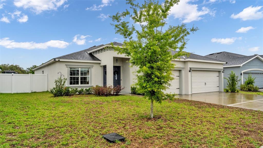 A single-story house with a light-colored exterior, a two-car garage, and a front yard — 1101 MONTGOMERY LANE, POLK CITY, FL