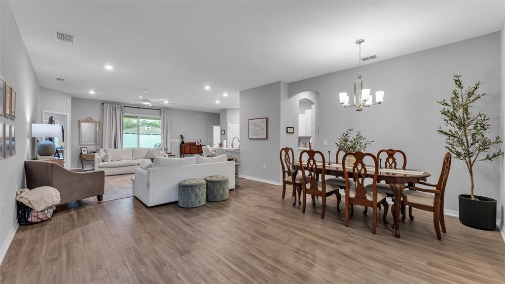 An open-concept living and dining area features light wood flooring and neutral gray walls — 1101 MONTGOMERY LANE, POLK CITY, FL