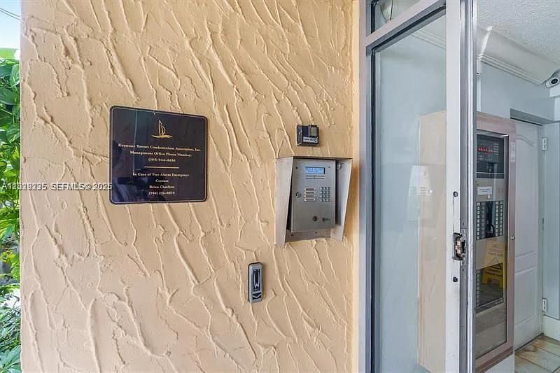 An exterior wall with a textured finish features a building directory, intercom, and glass door — 2000 NE 135th St # 609, North Miami FL 33181, NORTH MIAMI, FL