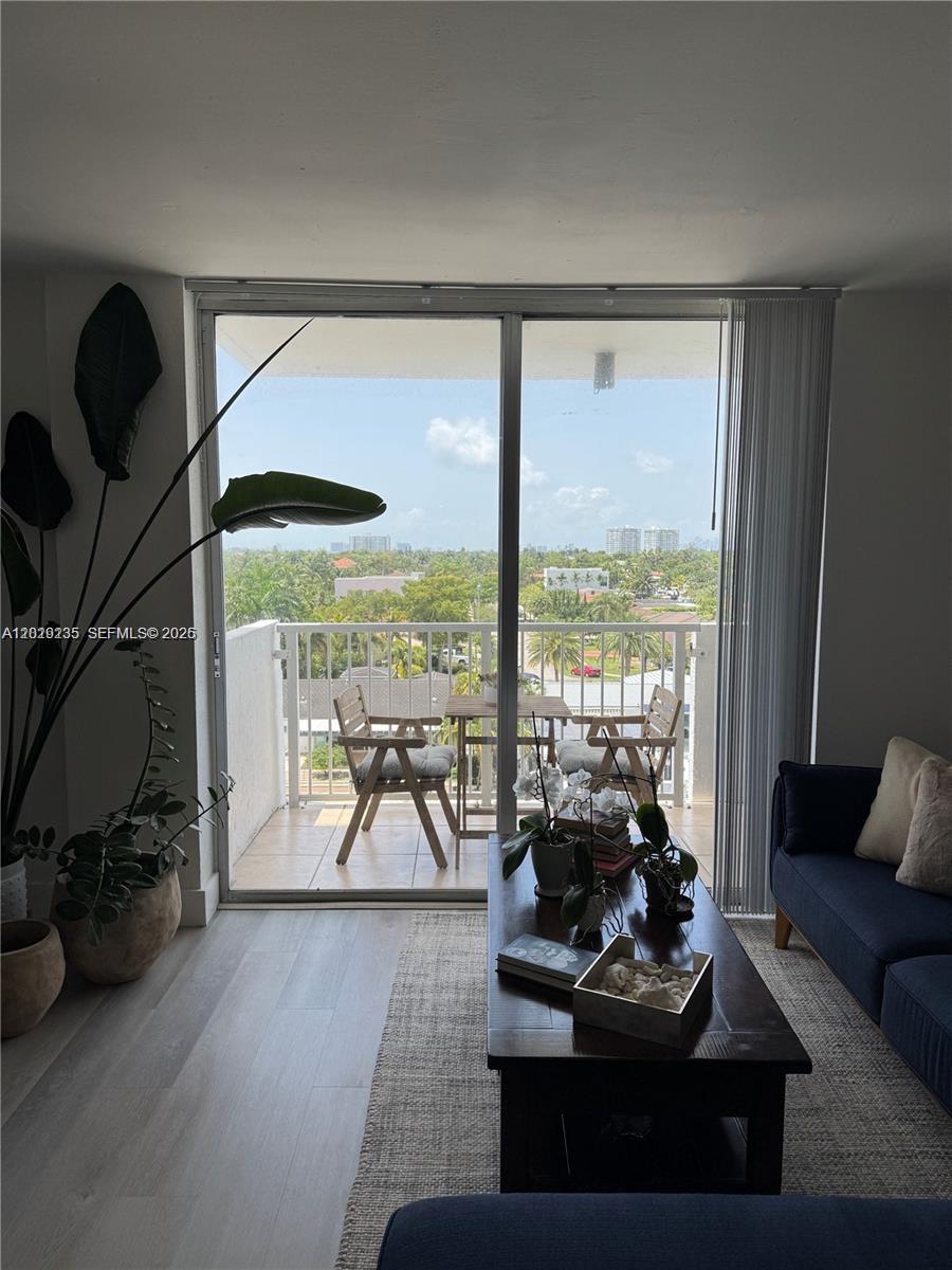 A living room with light wood floors opens onto a balcony with outdoor seating — 2000 NE 135th St # 609, North Miami FL 33181, NORTH MIAMI, FL