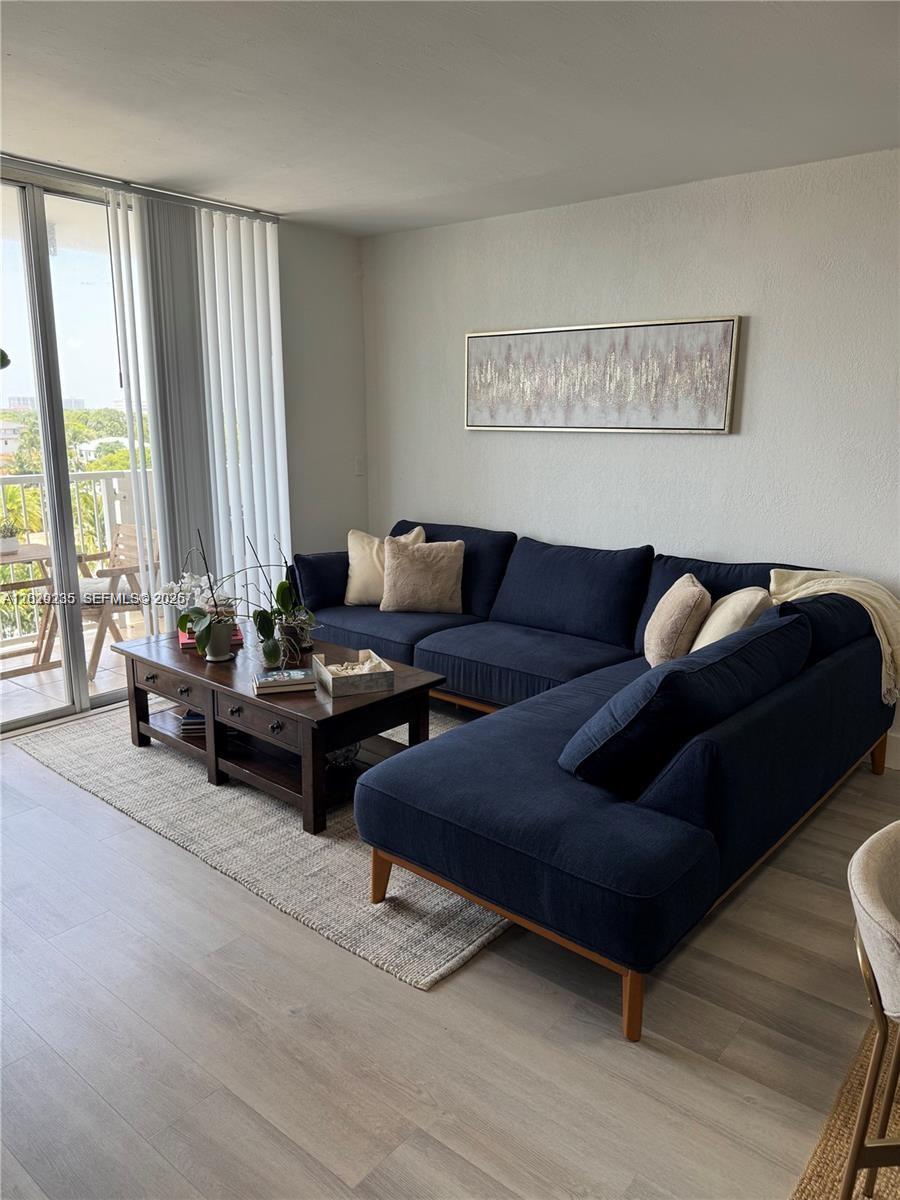 A living room features a navy blue sectional sofa, a wooden coffee table, and balcony access — 2000 NE 135th St # 609, North Miami FL 33181, NORTH MIAMI, FL
