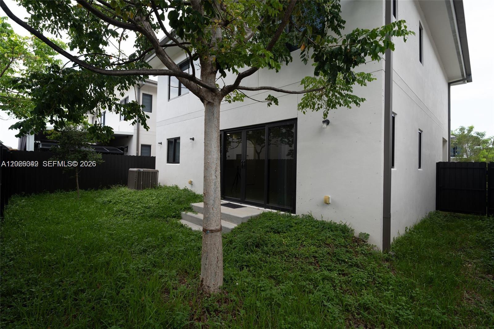 The exterior of a two-story white house features a small backyard with a tree — 1159 NW 3rd St, Florida City FL 33034, FLORIDA CITY, FL