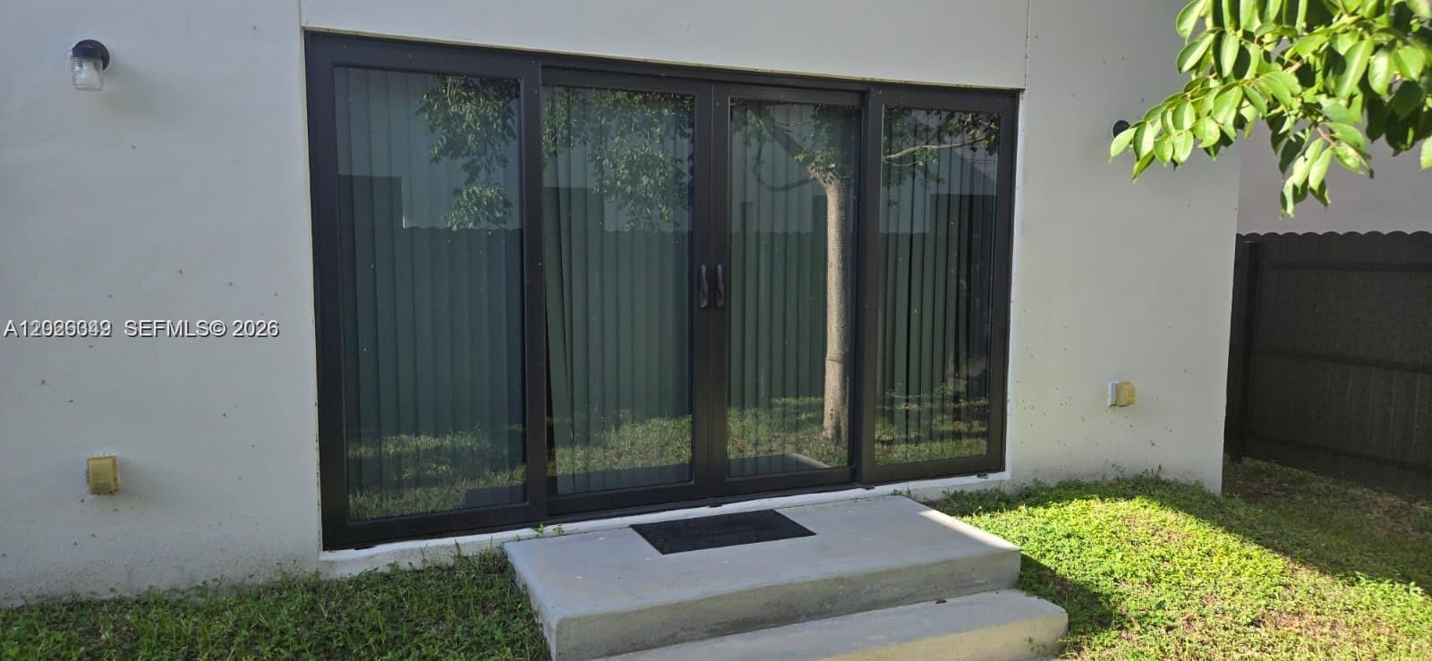 A sliding glass door with dark frames leads to a concrete step outside — 1159 NW 3rd St, Florida City FL 33034, FLORIDA CITY, FL