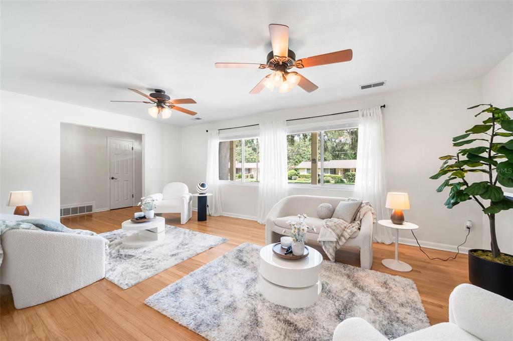 A bright living room features two ceiling fans, white furniture, and light wood flooring — 817 NW 37TH DRIVE, GAINESVILLE, FL