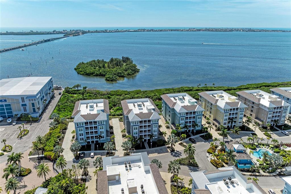 An aerial view shows several multi-story residential buildings located along a coastal waterfront — 392 ARUBA CIRCLE UNIT 102, BRADENTON, FL