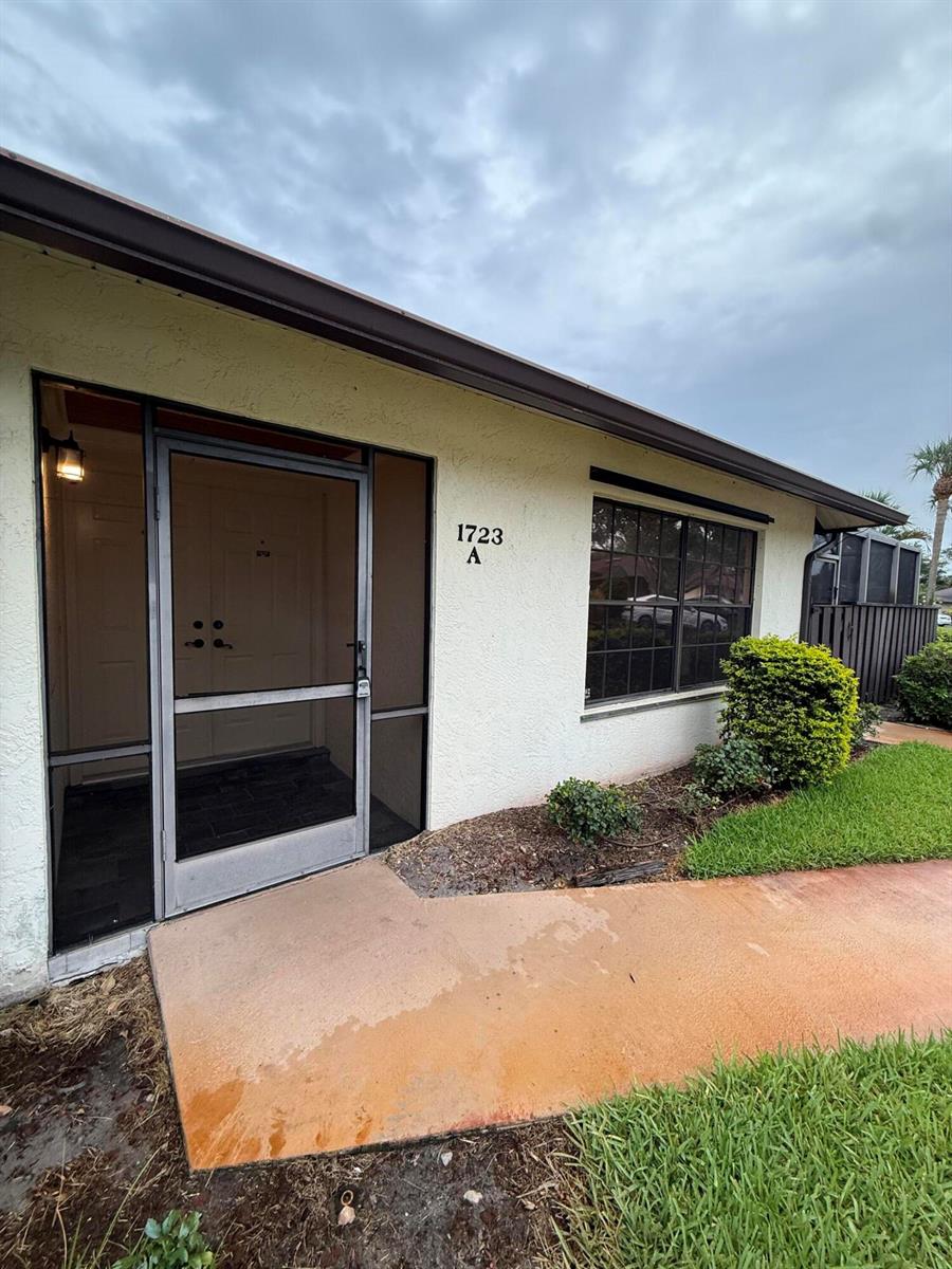 The exterior of a single-story residential unit features a screened front door and window — 1723 Mariners Cove # A, Fort Pierce FL 34950, FORT PIERCE, FL