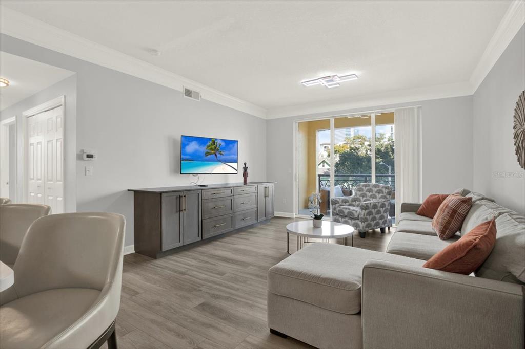 A living room features gray wood-look flooring, a sectional sofa, and a wall-mounted television — 345 BAYSHORE BOULEVARD UNIT 302, TAMPA, FL