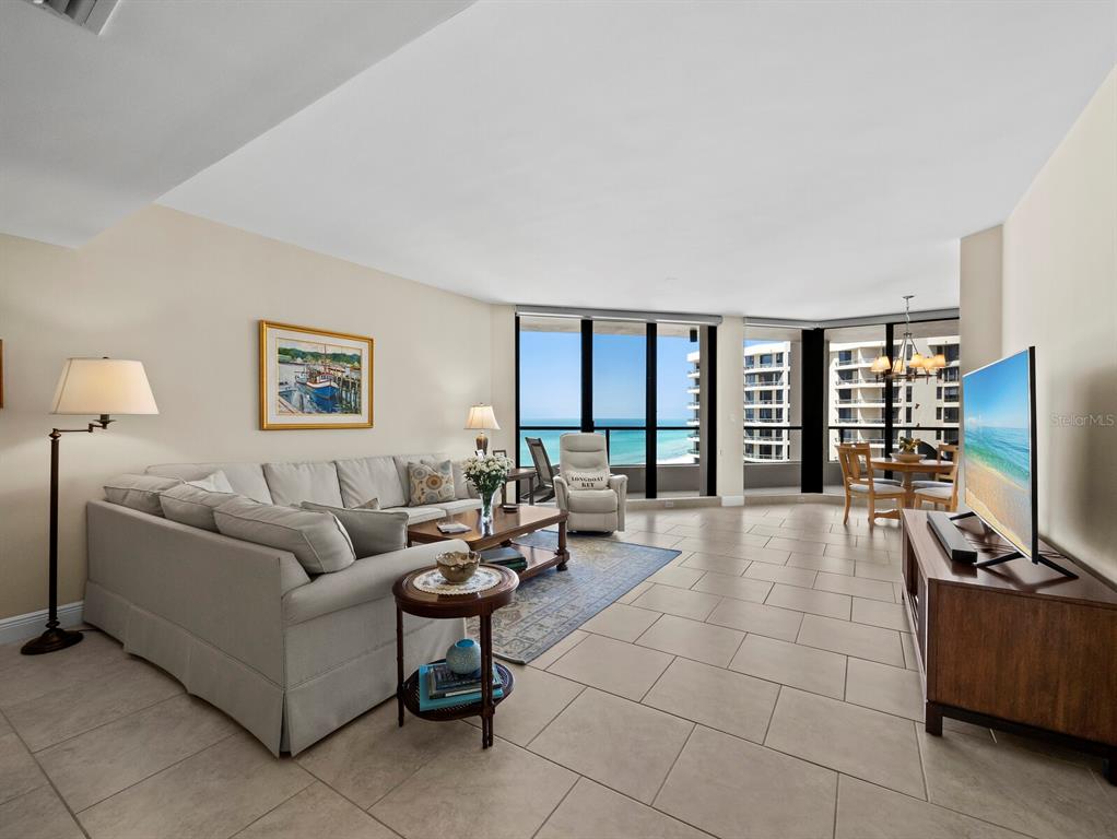 A living room with tile floors, a sectional sofa, and floor-to-ceiling windows overlooking the ocean — 1211 GULF OF MEXICO DRIVE UNIT 709, LONGBOAT KEY, FL