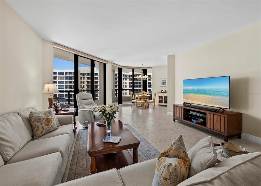A living room with tile floors, a television, and floor-to-ceiling windows overlooking a building — 1211 GULF OF MEXICO DRIVE UNIT 709, LONGBOAT KEY, FL