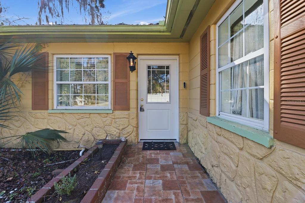 The exterior of a yellow house features a white front door, stone siding, and shutters — 10170 W YULEE DRIVE, HOMOSASSA, FL