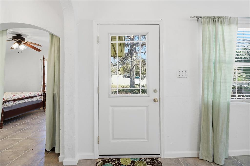 A white front door with a glass pane stands between a bedroom archway and curtains — 10170 W YULEE DRIVE, HOMOSASSA, FL