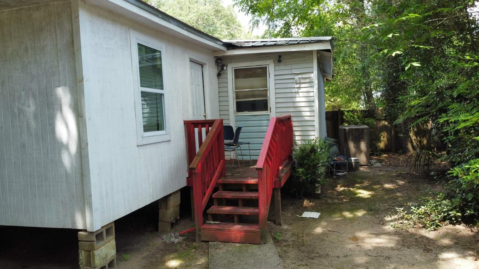 The exterior of a house features a red wooden deck with stairs and white siding — 25 Madison Street, FL 32324, FL