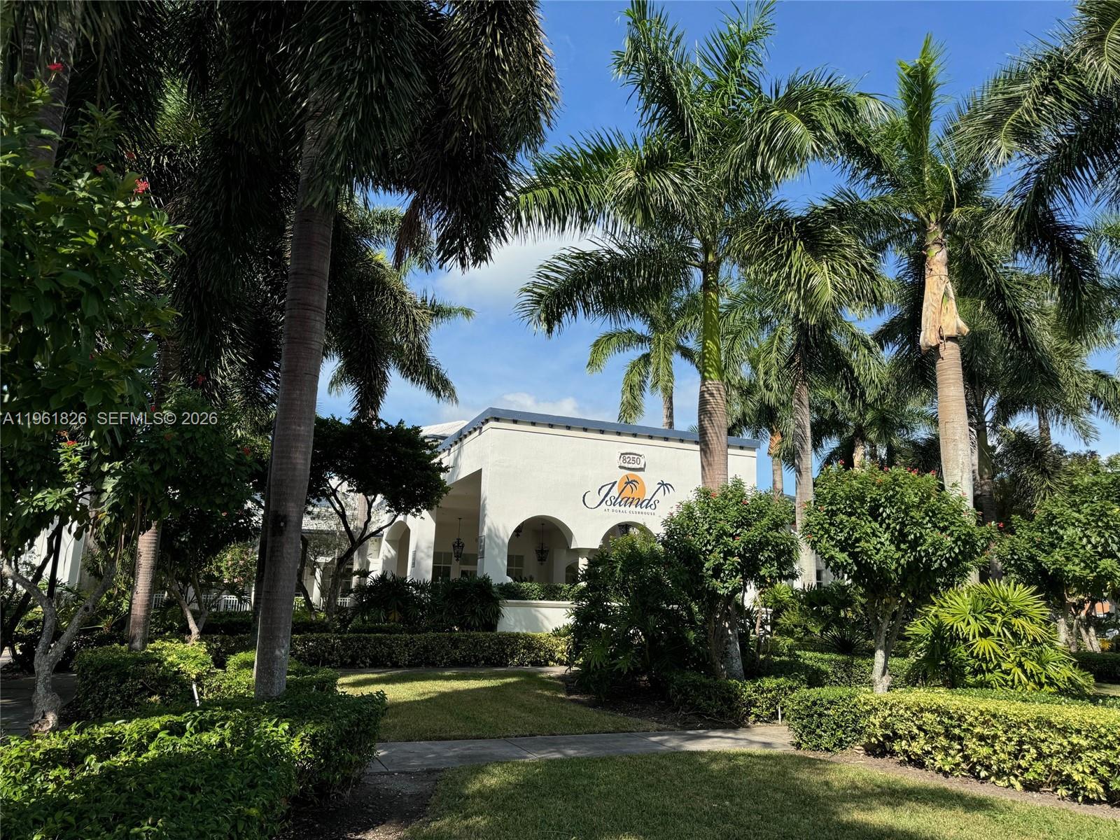 A white clubhouse building with arched entryways is surrounded by palm trees and landscaping — 11601 NW 89th St # 106, Doral FL 33178, DORAL, FL