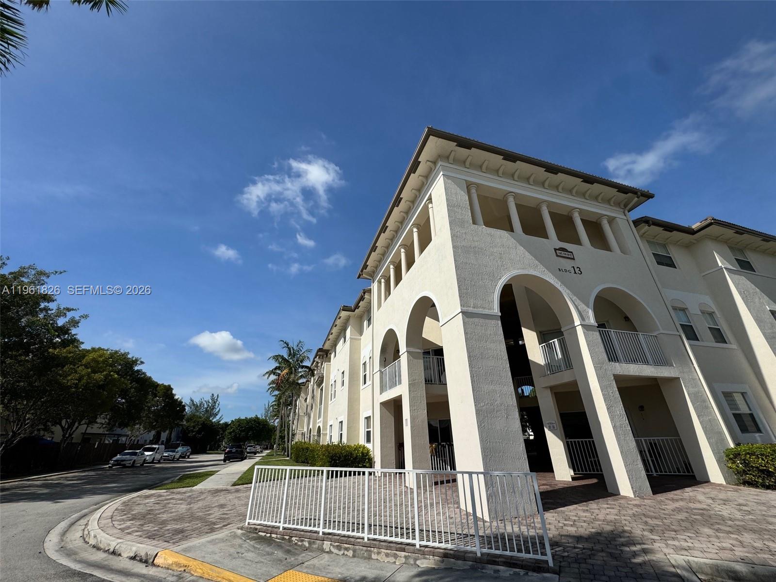 A low-angle exterior view of a multi-story apartment building labeled Building 13 — 11601 NW 89th St # 106, Doral FL 33178, DORAL, FL