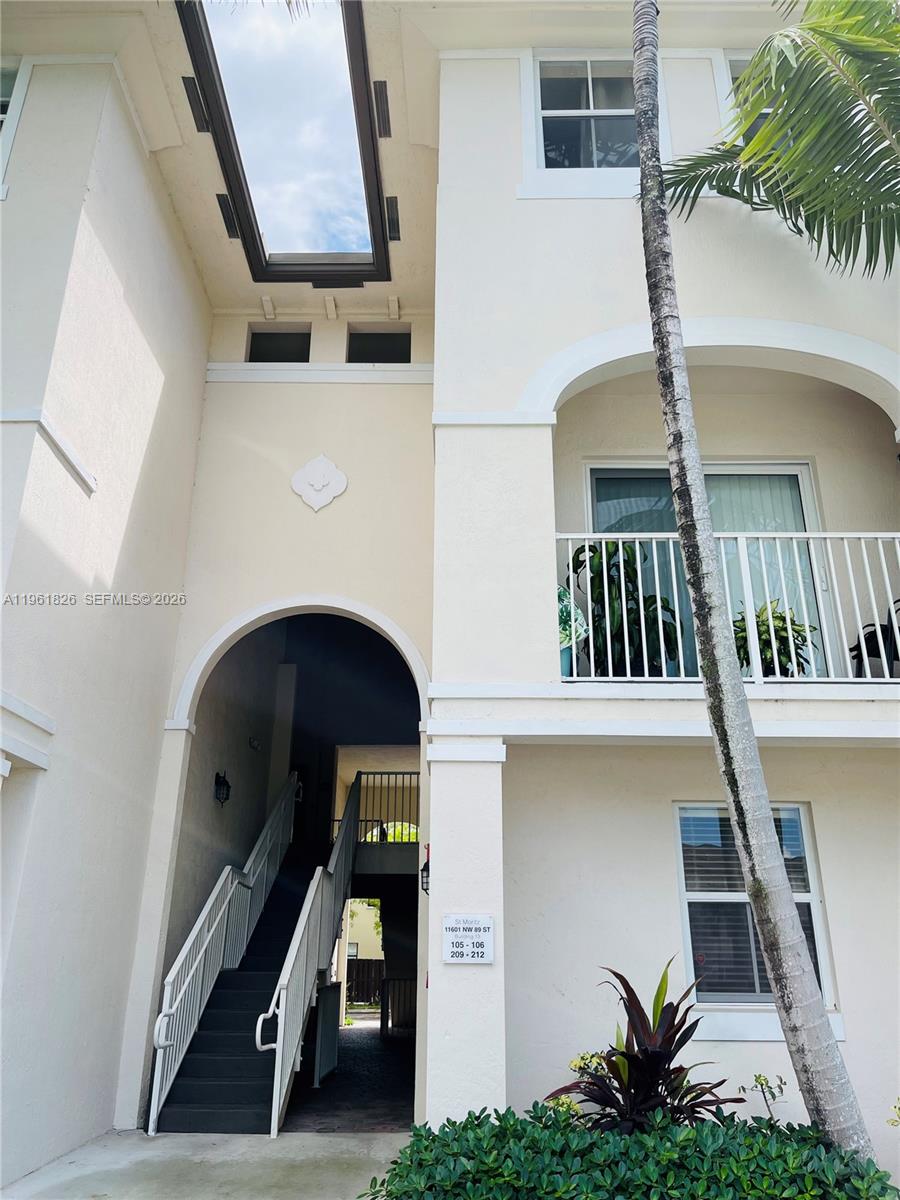 A low-angle exterior view shows a multi-story building with a staircase leading to upper units — 11601 NW 89th St # 106, Doral FL 33178, DORAL, FL