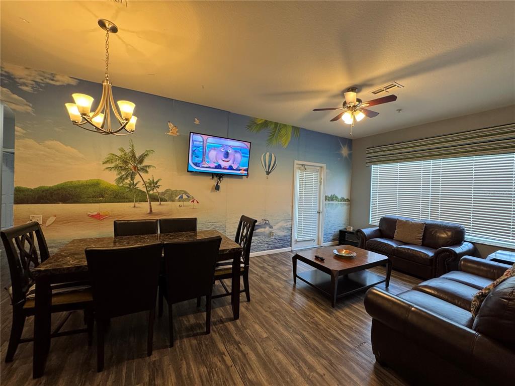 A living and dining room features a tropical mural, dark wood furniture, and leather sofas — 2305 SILVER PALM DRIVE UNIT 302, KISSIMMEE, FL