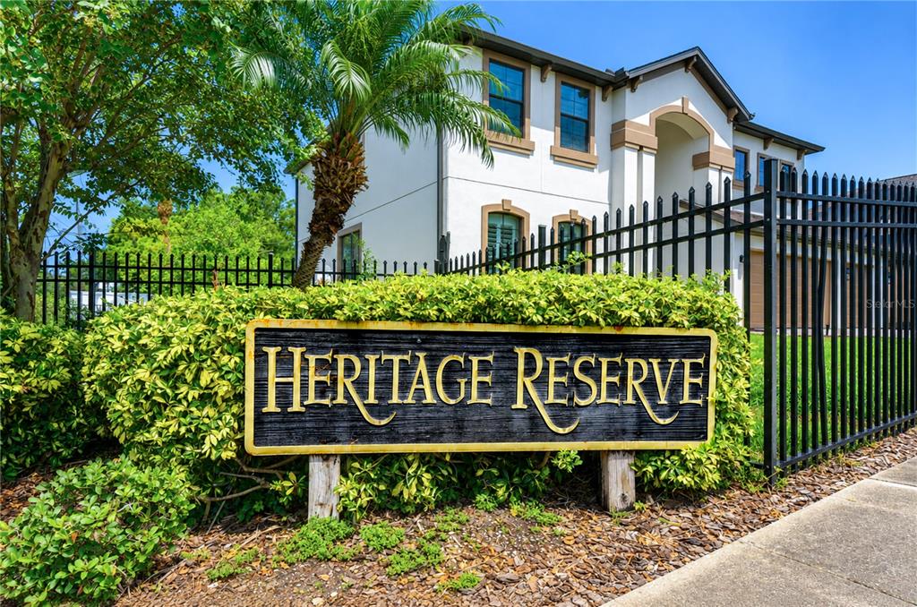 A sign for Heritage Reserve stands in front of a two-story house and black fence — 9451 59TH STREET N, PINELLAS PARK, FL