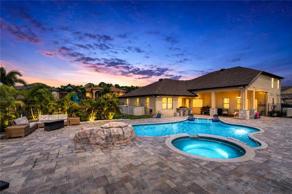 A backyard patio features a swimming pool, a hot tub, and a stone water feature — 9451 59TH STREET N, PINELLAS PARK, FL