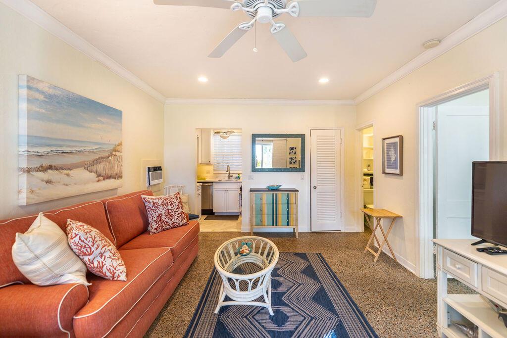 A living room features a coral sofa, a patterned rug, and a view into a kitchen — 88 S Ocean Boulevard, Delray Beach FL 33483, DELRAY BEACH, FL
