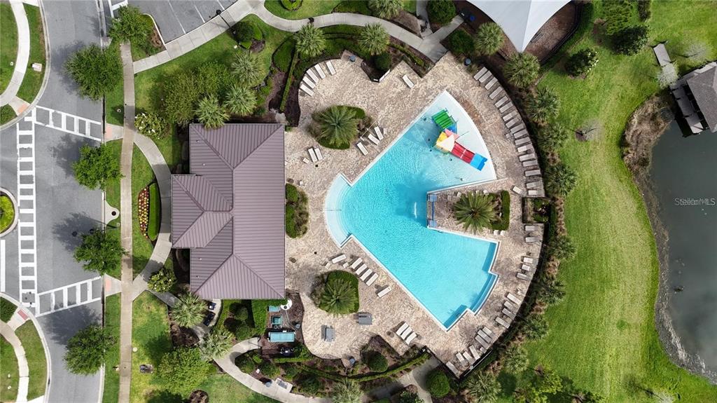 An aerial view shows a community swimming pool with a slide, deck, and adjacent building — 2695 NOTTEL DRIVE, ST CLOUD, FL