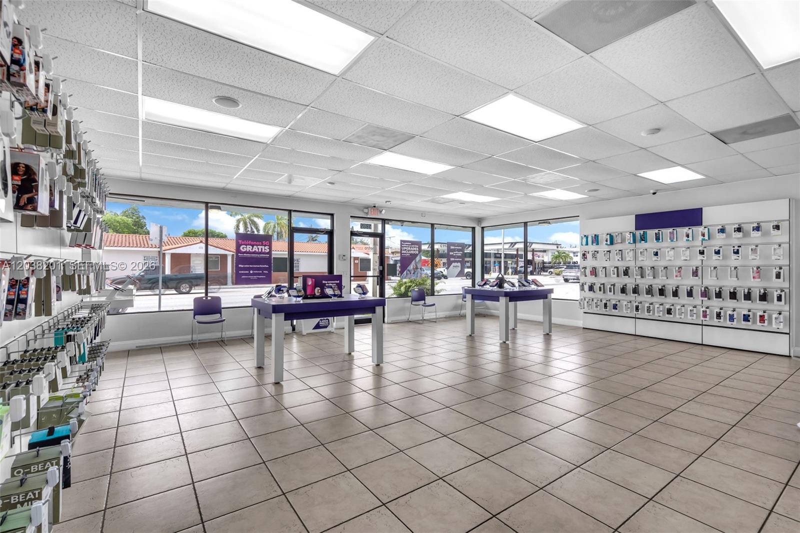 A retail store interior features tiled floors, drop ceilings, display tables, and wall-mounted product shelving — 1879 NW 7th St, Miami FL 33125, MIAMI, FL