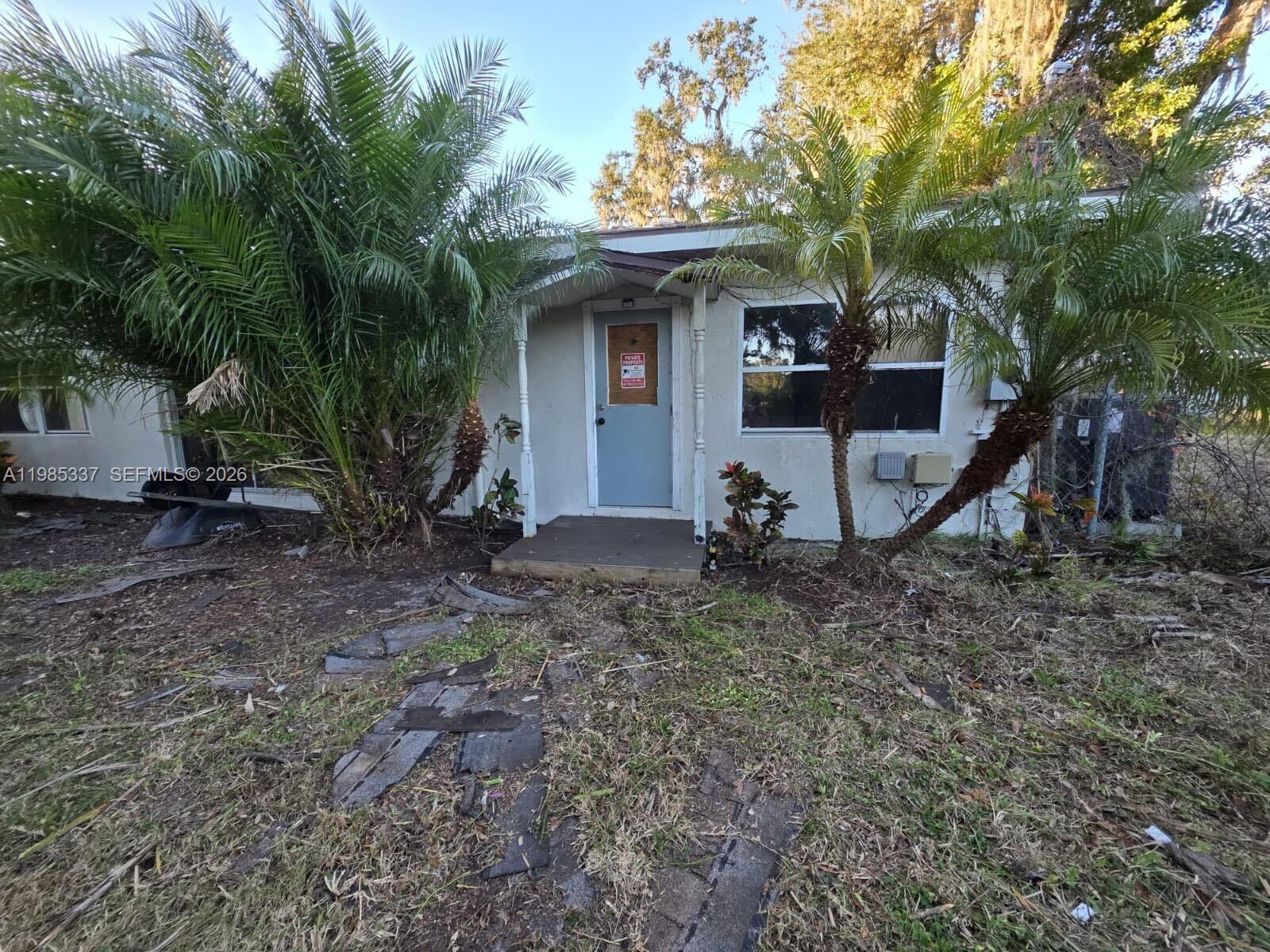 A small, single-story house exterior features a boarded-up front door and two large palm trees — 3661 Bernice LN, Sarasota FL 34238, SARASOTA, FL