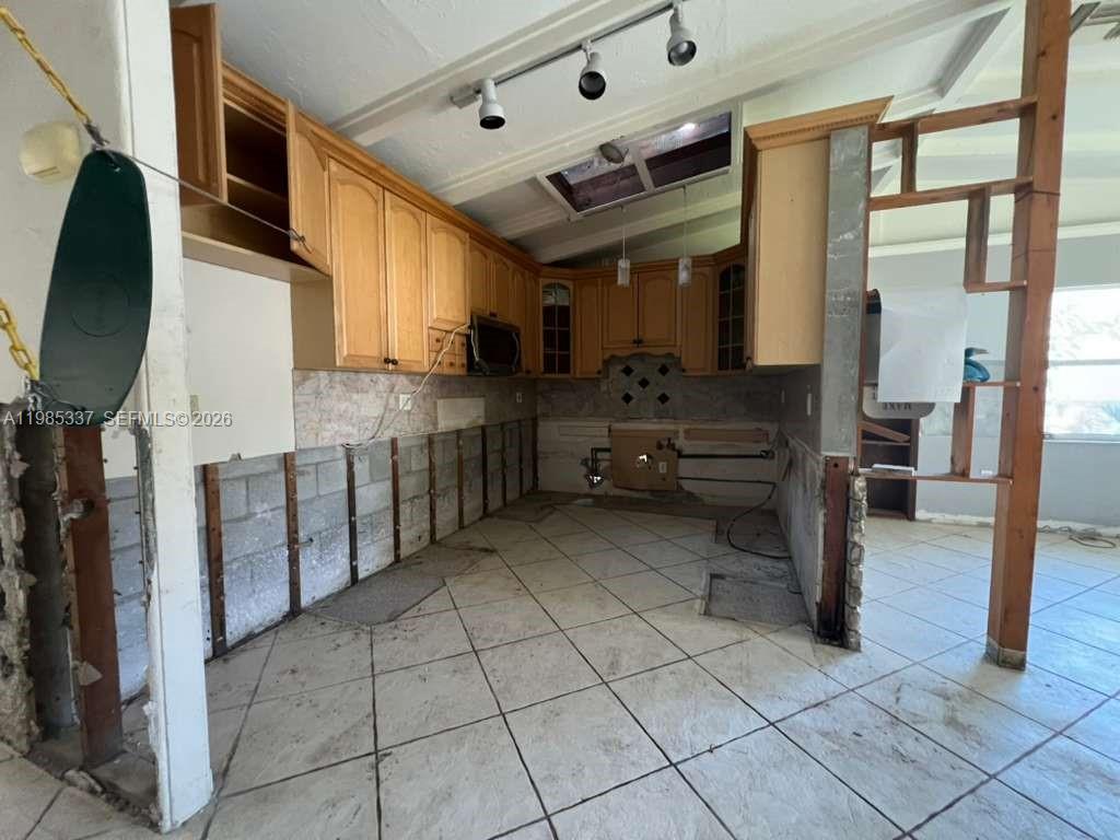 An unfinished kitchen features light wood cabinets, tiled flooring, and exposed concrete block walls — 3661 Bernice LN, Sarasota FL 34238, SARASOTA, FL