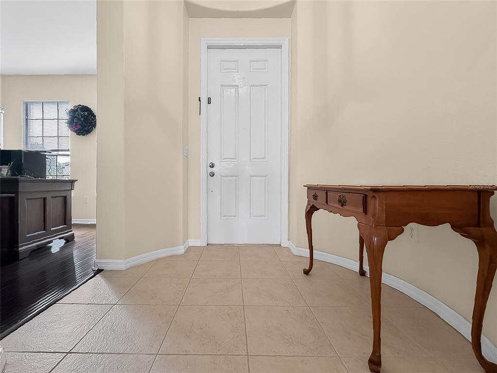 An entryway features beige tile flooring, a white front door, and a wooden console table — 25143 CHIPSHOT COURT, SORRENTO, FL