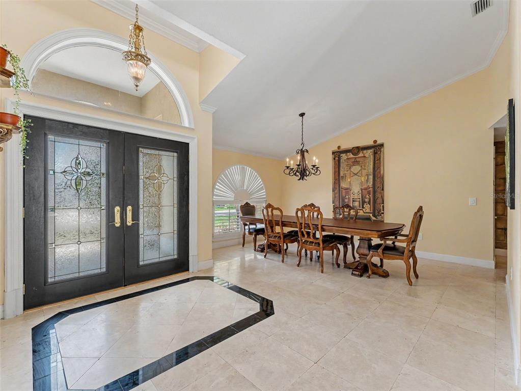 A dining area with a long wooden table, chairs, and a chandelier near the entrance — 6626 CRESCENT LAKE DRIVE, LAKELAND, FL