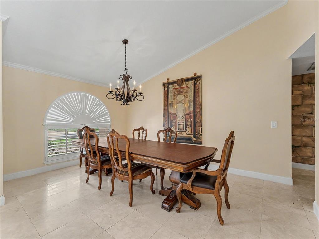 A dining room features a wooden table, six chairs, a chandelier, and a large wall tapestry — 6626 CRESCENT LAKE DRIVE, LAKELAND, FL