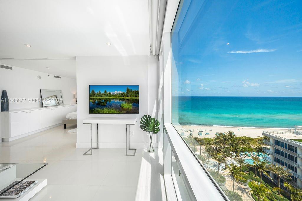 A bright, modern room features a wall-mounted television and floor-to-ceiling windows overlooking the ocean — 6801 Collins Ave # 1206, Miami Beach FL 33141, MIAMI BEACH, FL