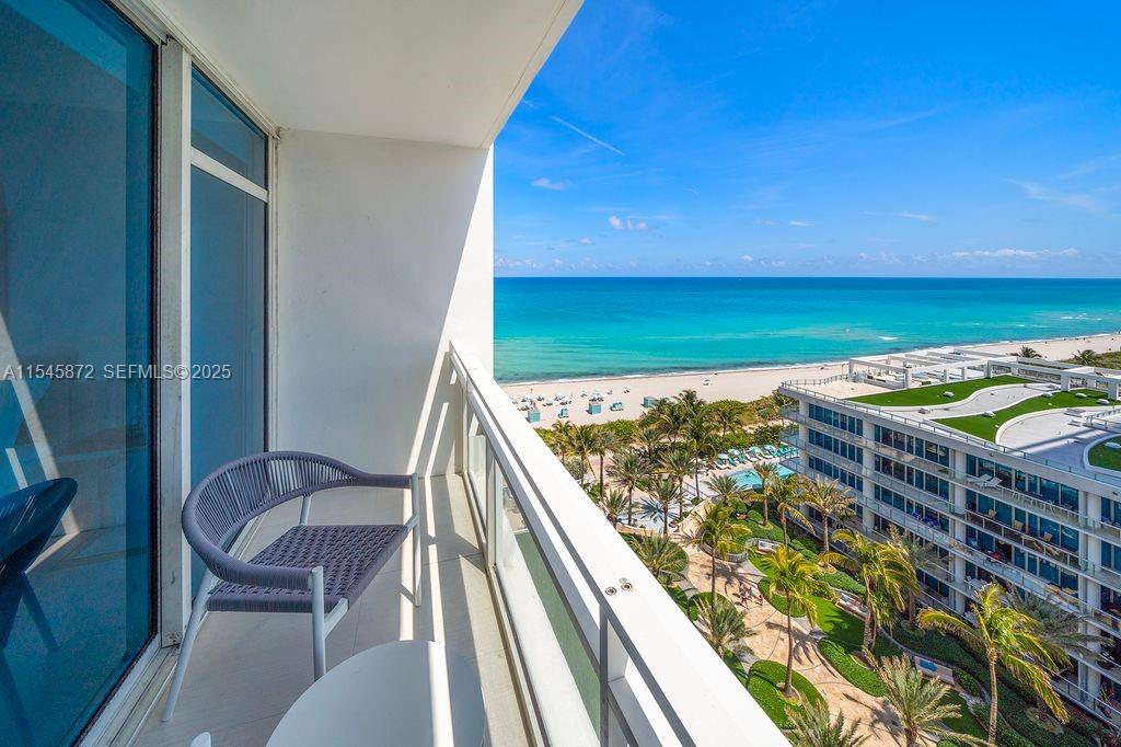 A balcony with a chair overlooks a beach, the ocean, and a nearby resort complex — 6801 Collins Ave # 1206, Miami Beach FL 33141, MIAMI BEACH, FL