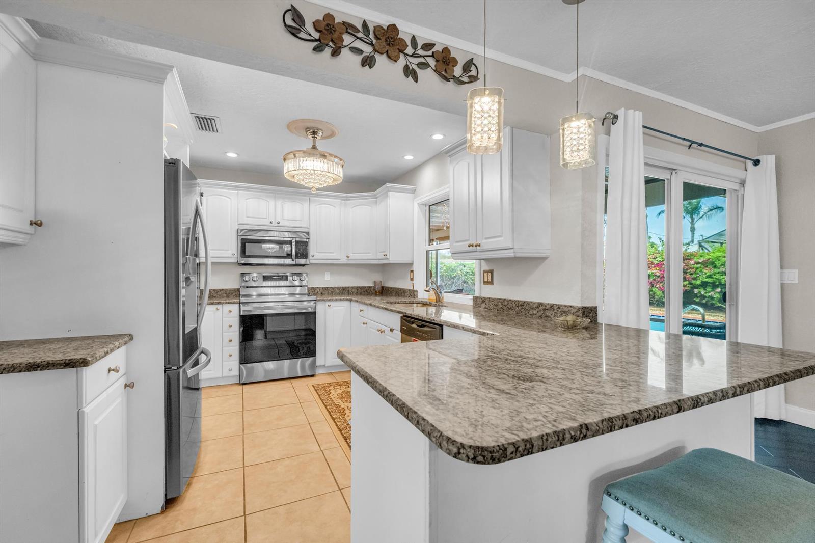 A kitchen features white cabinets, granite countertops, stainless steel appliances, and a breakfast bar — 4167 Russell Street, Jupiter FL 33469, JUPITER, FL