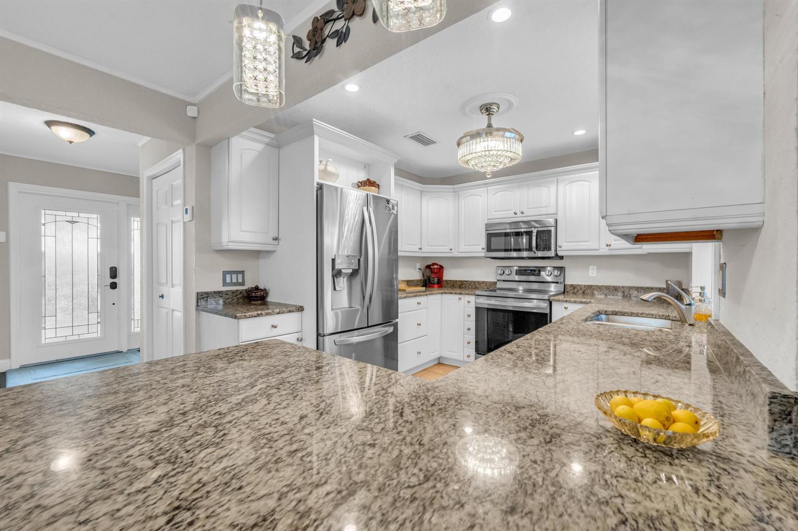 A kitchen with white cabinets, granite countertops, stainless steel appliances, and a breakfast bar — 4167 Russell Street, Jupiter FL 33469, JUPITER, FL